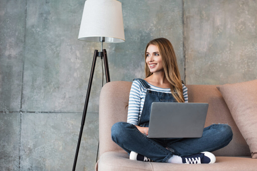 אישה יושבת על ספה עם לפטופ